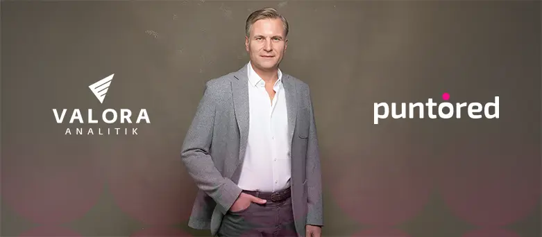 Andrés Albán en pose ejecutiva junto a los logos de Puntored y Valora Analitik